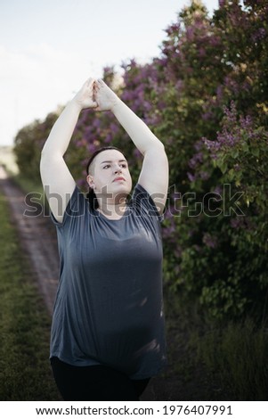 overweight woman doing yoga on the country road