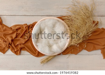 Bohemian rustic newborn background - white bowl with macrame and dry wheat on white wooden floor.