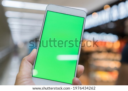 Green blank screen Mock Up phone for advertising. Digital Smartphone holding mobile for information internet at anywhere in blur background. Technology internet of things for new generation