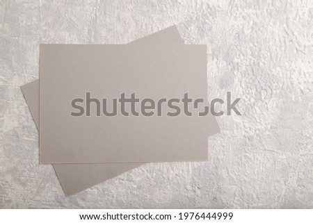 Gray paper business card, mockup on gray concrete background. Blank, flat lay, top view, still life, copy space.