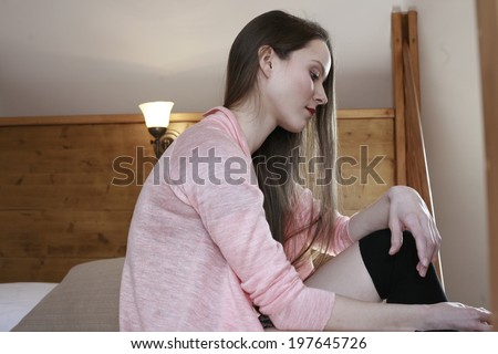 young beautiful woman on the bed happy dreamy beauty girl hugging her legs while siting in bed against the wooden wall