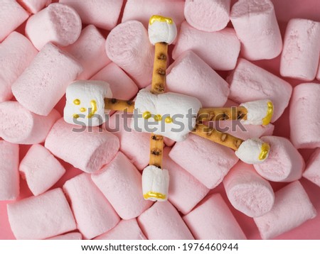 A man made of white marshmallows on a background of large pink marshmallows. A collage of sweets. Flat lay.