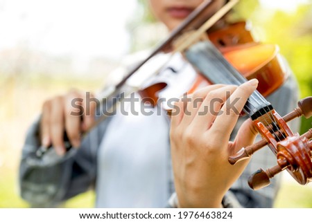 Close-up portrait of Young Asia woman music violinist hand play violin, relax in the garden with peace of mind.