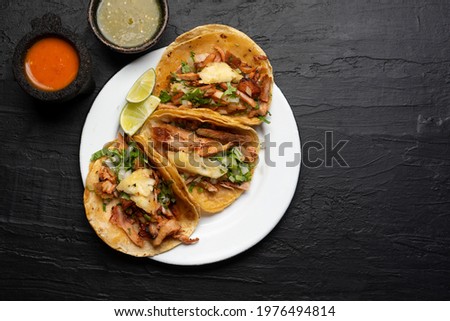 Pork tacos called al pastor with pineapple on dark background. Traditional mexican tacos