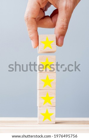 Hand holding wooden blocks with the star symbol. Customer reviews, feedback, rating, ranking and service concept. Royalty-Free Stock Photo #1976495756