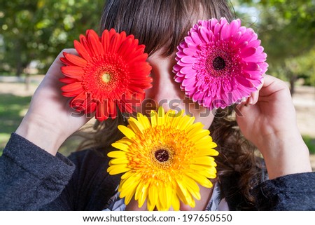 Cute girl hide her eyes and mouth by gerbera flowers