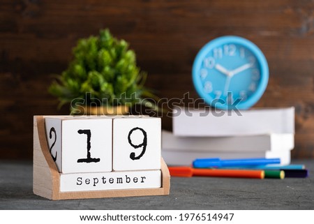 September 19th. September 19 wooden cube calendar with blur objects on background.