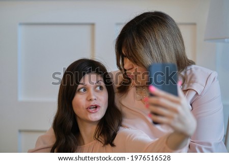Aged woman and her adult daughter take a selfie on a smartphone. intergenerational relations concept. Family and technology.