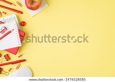 Above photo of notepad sharpener pencil pen keyboard felt-tip paperclips computer mouse and apple isolated on the yellow background with blank space