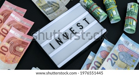 Lightbox board with word INVEST in black letters around euro banknotes. Money, Business, finance, investment, saving. Cash bill. Business budget of wealth and prosperity finance. Passive income