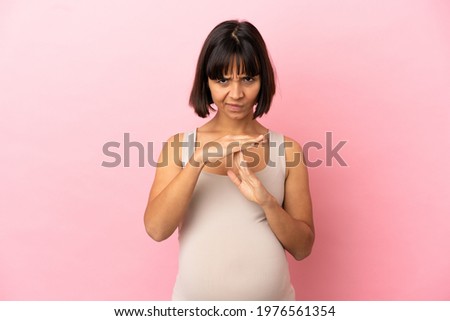 Young pregnant woman over isolated pink background making time out gesture