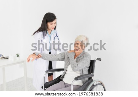 asian female doctor talk about disease symptoms with old stroke patient in hospital, doctor touch on shoulder of patient and asses to treatment , rehabilitation process, elderly healthcare promotion Royalty-Free Stock Photo #1976581838