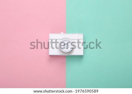 Creative layout. White retro camera on blue pink background. Pastel color trend. Minimalism. Concept art. Modern still life. Flat lay. Top view.