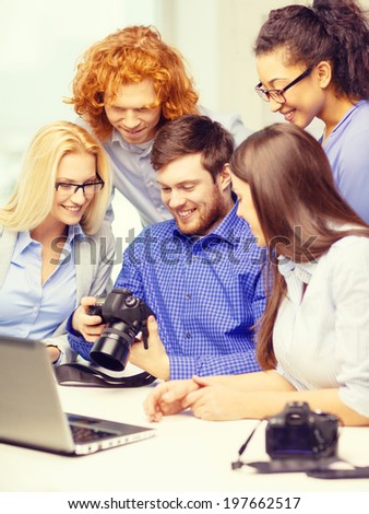 business, office and startup concept - smiling creative team with laptop computer and photocamers working in office