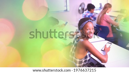 Composition of light circles over african american female teenager using smartphone in classroom. global communication and social networking concept digitally generated image.