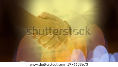 Composition of businessman handshake with glowing yellow spots of light. business and success concept digitally generated image.