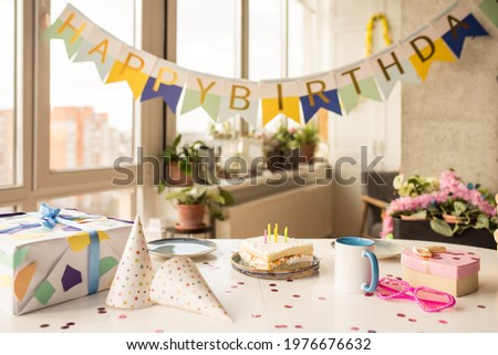 Birthday party table with birthday cake with candles, balloons and colored decor