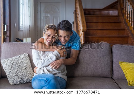 Happy middle age mother spend time with teenager son, relatives people hugging at home, adult attentive millennial grateful child wrapped in a plaid or warm sweater loving mommy caring  Royalty-Free Stock Photo #1976678471
