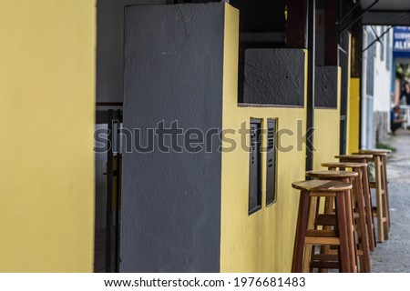 front of a bar with yellow walls and chairs outside the counter