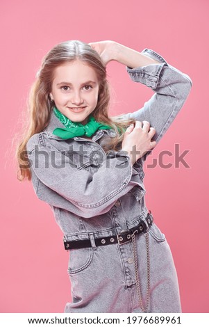 Youth fashion. Portrait of a cute teenage girl in modern clothes smiling at camera on a pink background.