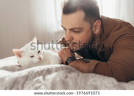 Man bonding to his white fluffy cat while spending time together at the bed