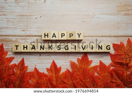 Happy Thanksgiving alphabet letter with autumn leaves on wooden background