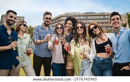 portrait of trendy young people drinking cocktails in plastic glasses. youth culture concept