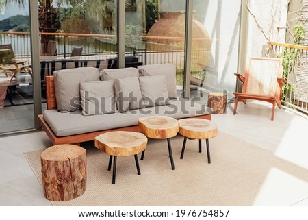 Wooden sofa and coffee tables on cozy stylish modern terrace, patio, backyard. Natural eco materials