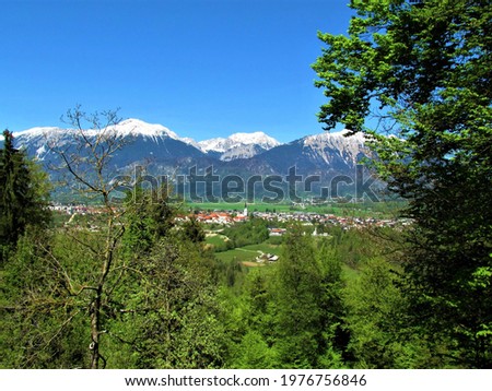 Beautiful view of the town of Radovljica in Gorenjska, Slovenia and snow covered peak of Karavanke mountains with trees in  front Royalty-Free Stock Photo #1976756846