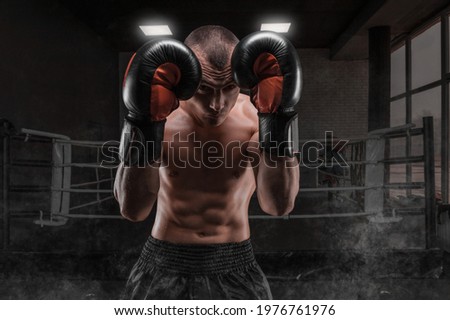 Image of a boxer in the gym. He covers his head with gloves. Protective rack. Mixed martial arts. Sports concept.