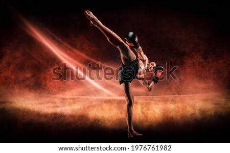 Image of a kickboxer in a fiery arena. Knee kick. Mixed martial arts. Sports concept.