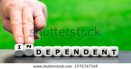 Hand turns dice and changes the word "dependent" to "independent". Royalty-Free Stock Photo #1976767568