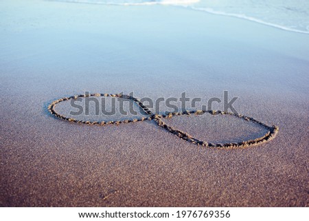 Eternity symbol on a wet glowing sand reflecting sky. Hand drawn 8 on a beach at seaside