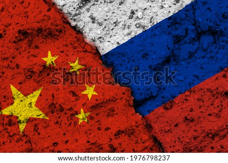Concept of a Competition between the Peoples Republik of China and the Russian Federation with painted flags on a wall with a crack