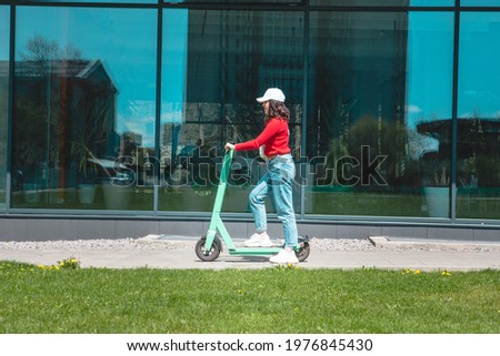 young woman riding electric kick scooter copy space spring sunny day