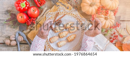 Senior woman wrinkled hands top view, cooking process. Christmas, autumn holiday, bakery, fruits, vegetables, wooden table, old book recipes. Sharing family tradition. Healthy, thanksgiving food.