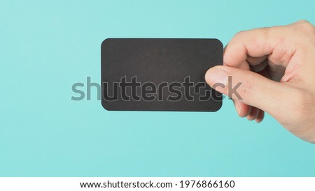 Empty space for text.Male hand holding black blank card isolated on mint green or Tiffany Blue background.