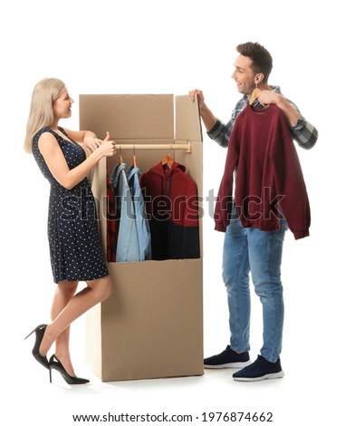 Young couple unpacking clothes on white background