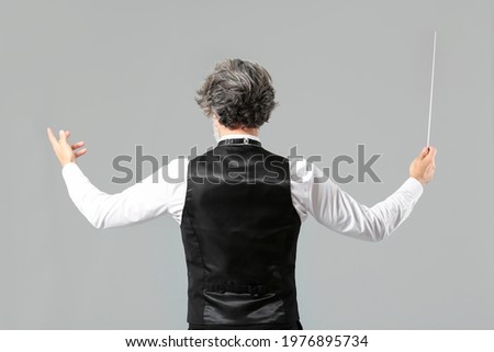 Senior male conductor on grey background Royalty-Free Stock Photo #1976895734