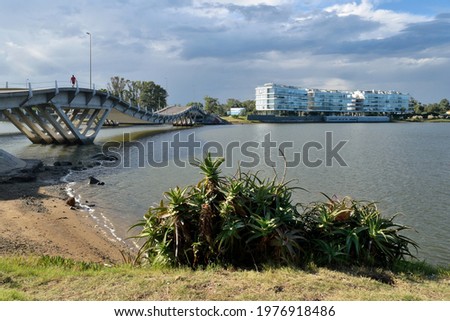 Photography of a bridge over a river and the skyline behind under a cloudy sky
