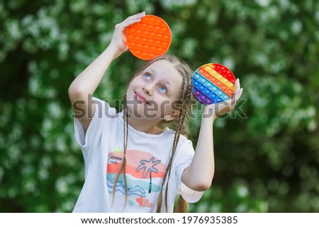 Cute child playing with the Pop It fidget. Push pop bubble flexible fidget sensory toy provide discharge and are good for the development of kid.