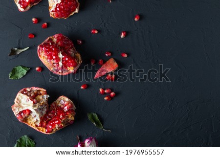 Ripe red pomegranate with fresh juicy seeds on a dark background. Natural vitamins. Healthy food concept. Food background. Flat lay with copy space.