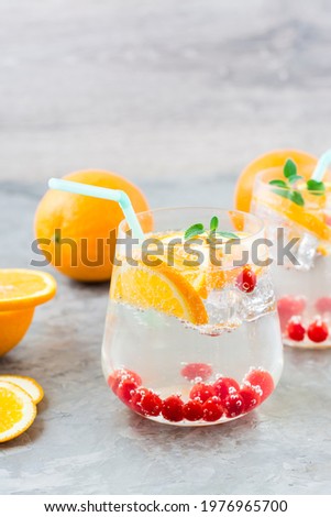 Hard seltzer cocktail with orange, cranberry and mint in glasses on the table. Alcoholic beverage. Vertical view Royalty-Free Stock Photo #1976965700