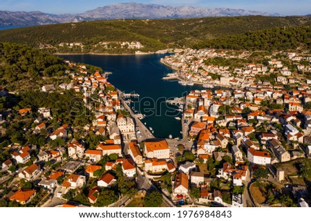 Red roofs and white stone houses in deep bay in village Pucisca on island Brac in Croatia. Aerial panoramic drone picture in august 2020