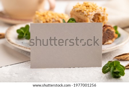 Gray paper business card and set of eclair on gray concrete background. side view, close up, selective focus, still life. Breakfast, morning, concept.
