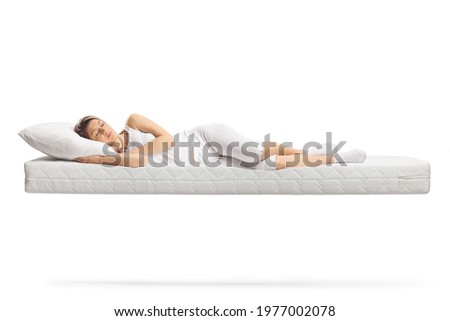 Young woman in white pajamas sleeping on a floating mattress isolated on white background Royalty-Free Stock Photo #1977002078