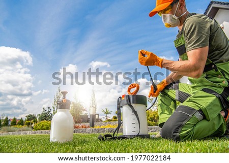 Caucasian Worker in His 40s Preparing Pest Control Spraying Equipment. Spring Garden Maintenance Theme. Royalty-Free Stock Photo #1977022184