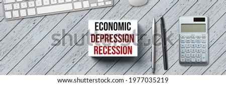 lightbox with the message ECONOMIC DEPRESSION - RECESSION and office equipment on wooden background