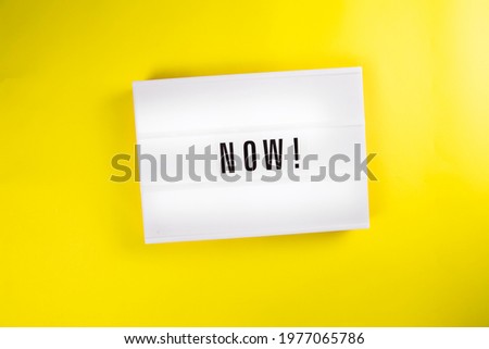 Lightbox with message NOW isolated on yellow background. Concept of motivation, hurry up sale announcement, start, beginning, buy now, register, join immediately, in stock, new trends, presently