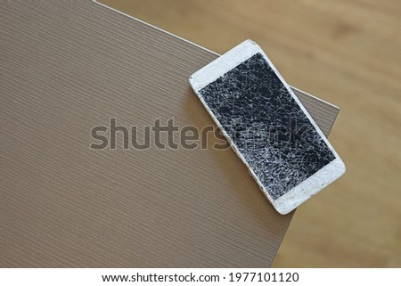 White smartphone with broken screen on wooden table background